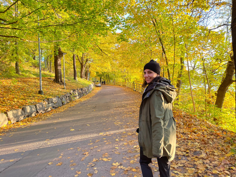 Woman in Finland surrounded by golden fall foliage during ruska season